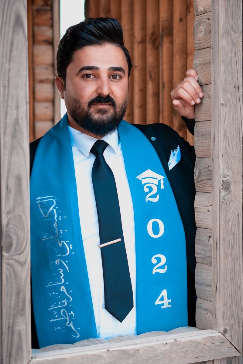 A graduate holding her diploma in front of a bookshelf